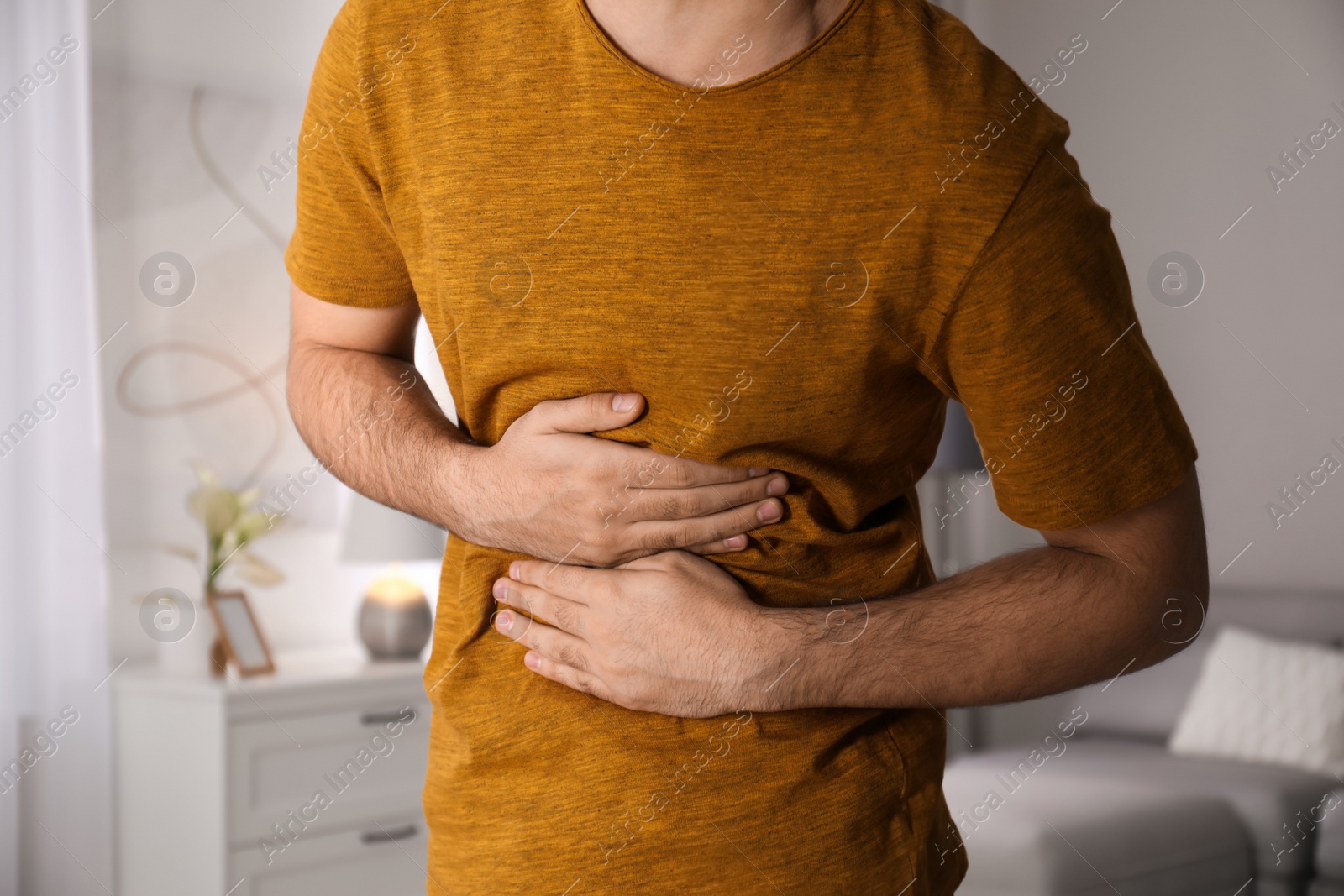 Photo of Young man suffering from stomach ache at home, closeup. Food poisoning