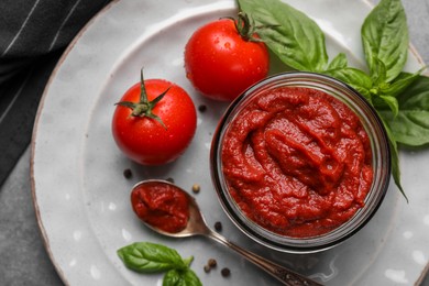 Photo of Jar of tasty tomato paste and ingredients on table, top view