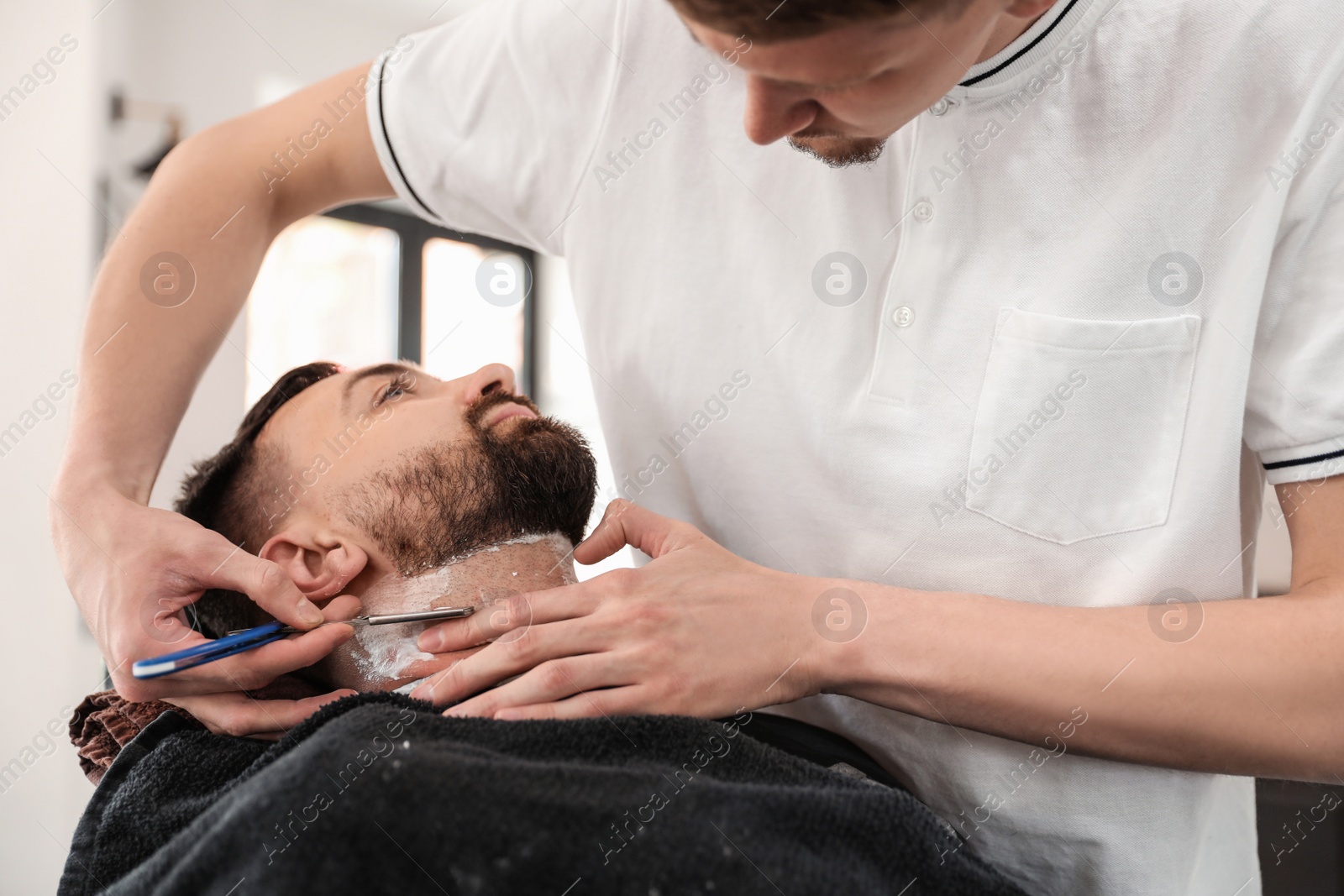 Photo of Professional barber working with client in hairdressing salon. Hipster fashion