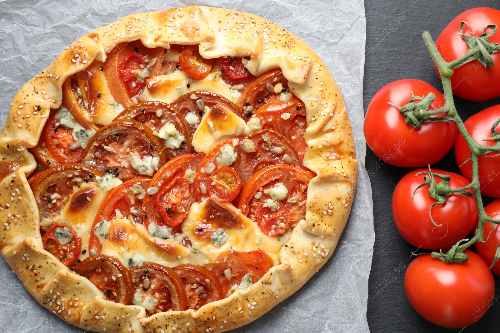 Photo of Tasty galette with tomato and cheese (Caprese galette) on dark table, top view