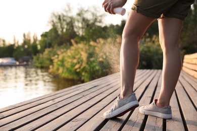 Photo of Woman applying insect repellent onto leg at pier, closeup. Space for text