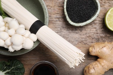 Photo of Cooking delicious ramen soup. Different ingredients on wooden table, flat lay