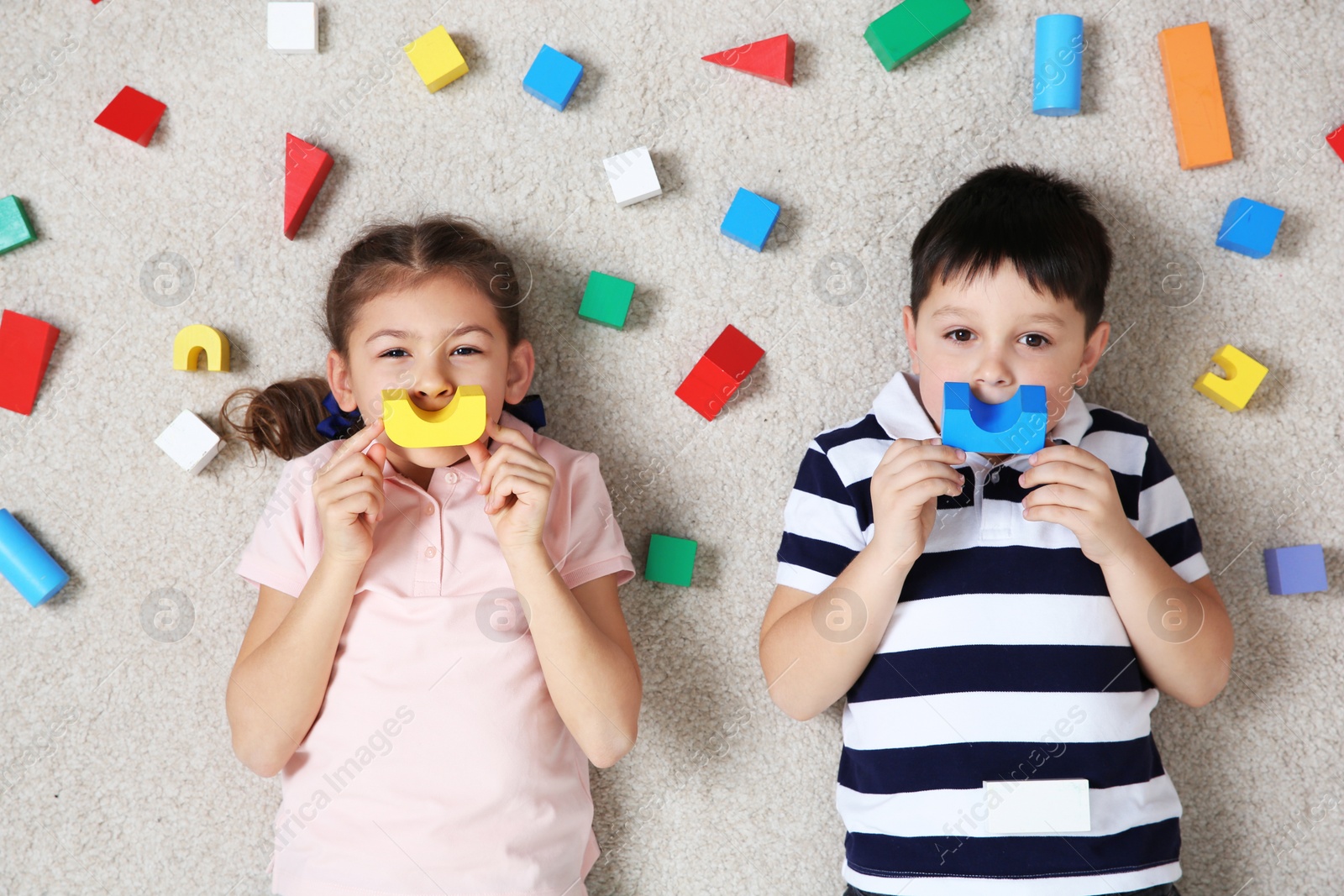 Photo of Cute children playing with colorful blocks on floor indoors, top view