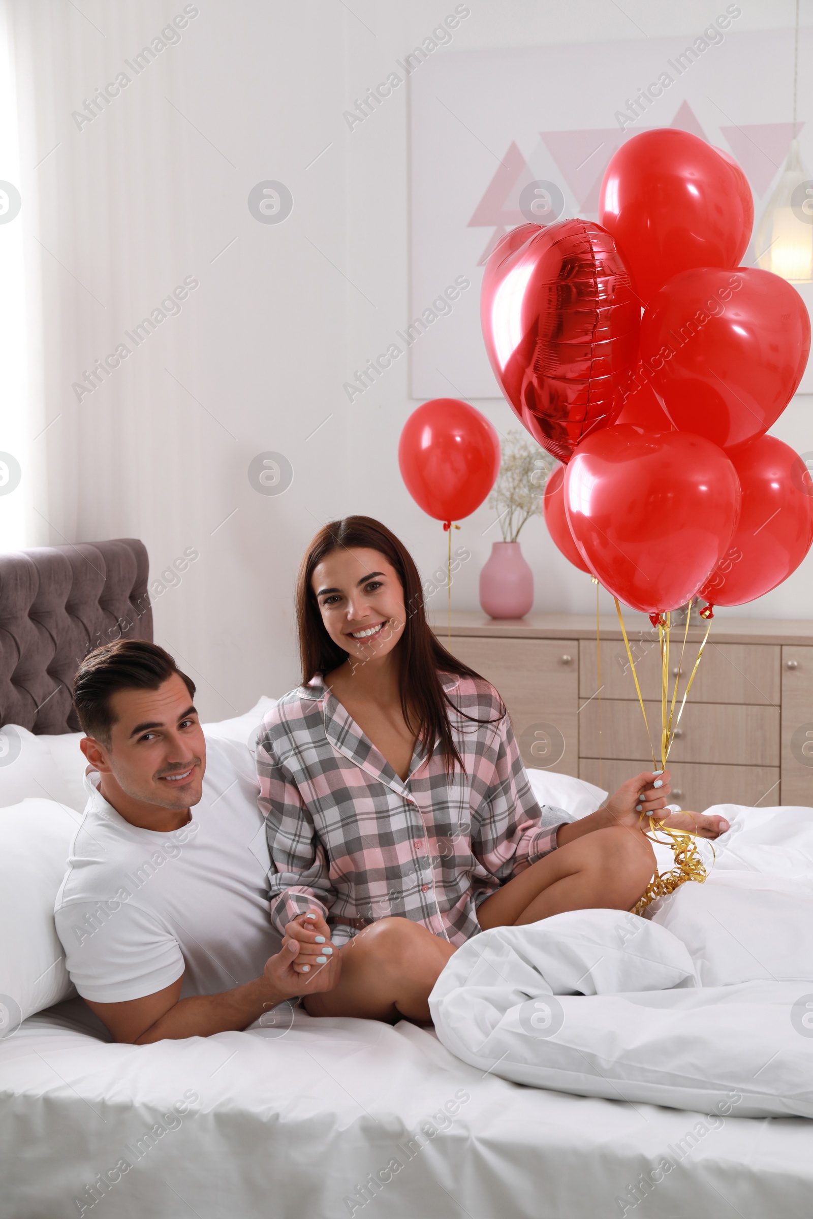 Photo of Beautiful couple with heart shaped balloons in bedroom