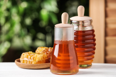 Photo of Tasty honey on table against green blurred background