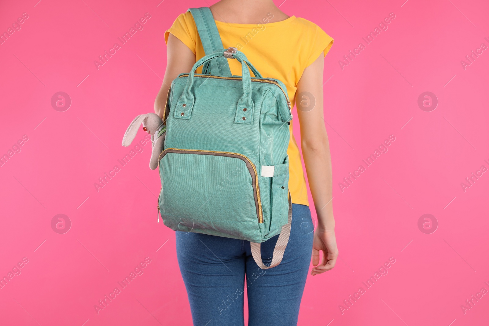 Photo of Woman with maternity backpack for baby accessories on color background, closeup