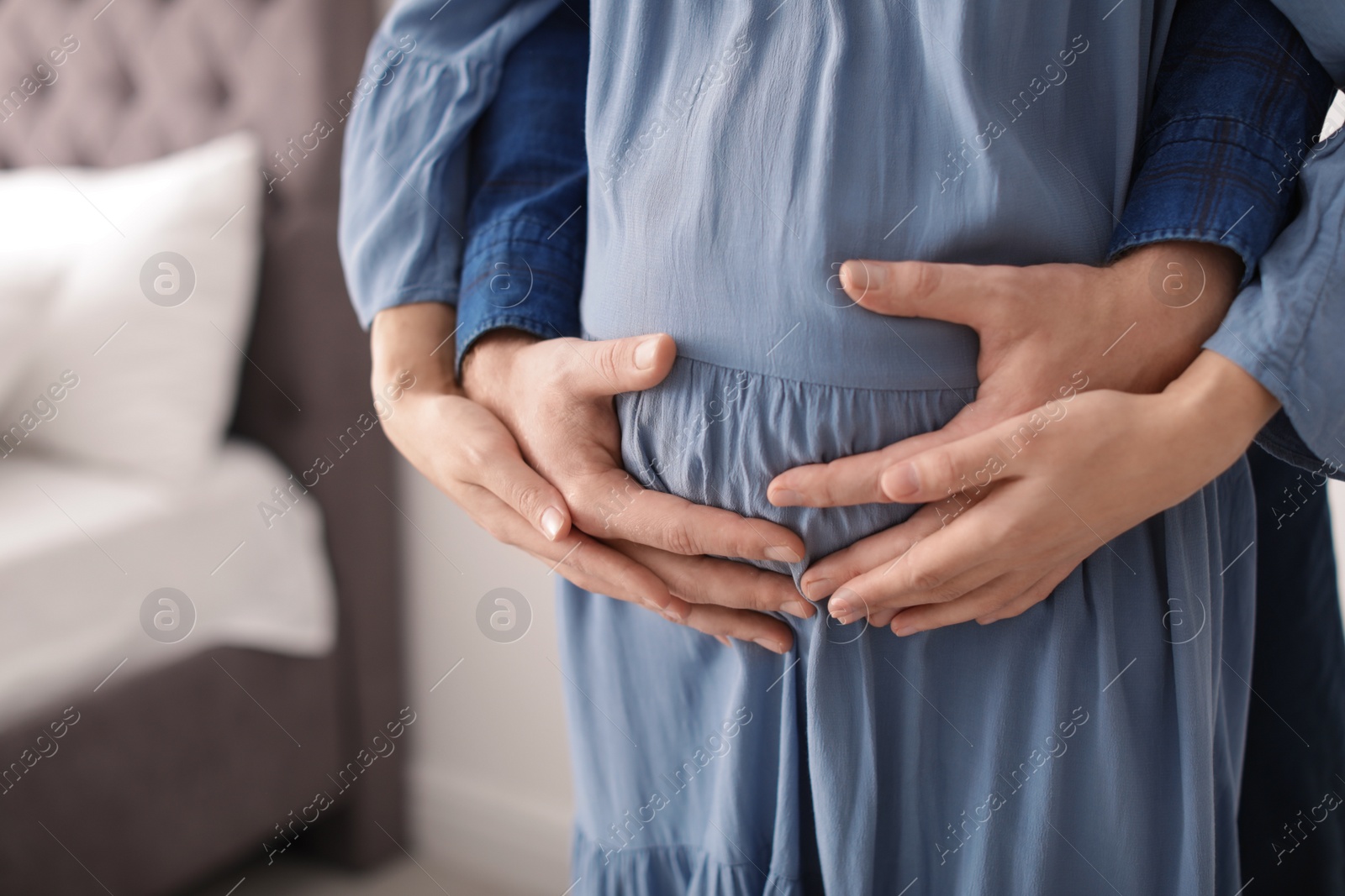 Photo of Young pregnant couple at home, closeup of hands