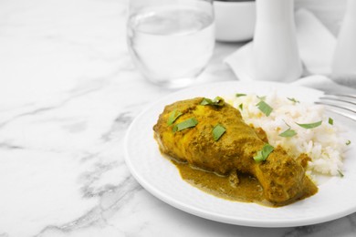 Delicious rice and chicken with curry sauce served on white marble table, closeup. Space for text