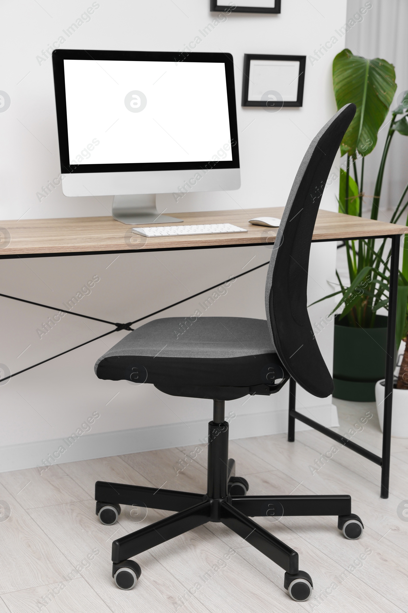 Photo of Comfortable office chair near desk in modern workplace