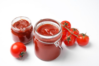 Photo of Jars with homemade tomato sauce and fresh vegetables on white background