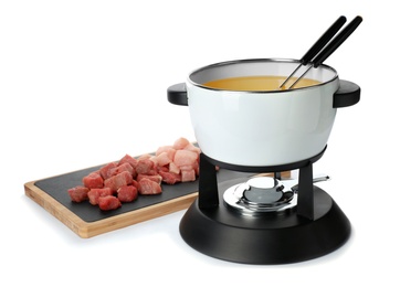 Fondue pot with oil and raw meat on white background