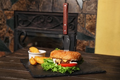 Photo of Tasty burger and fries served on slate plate