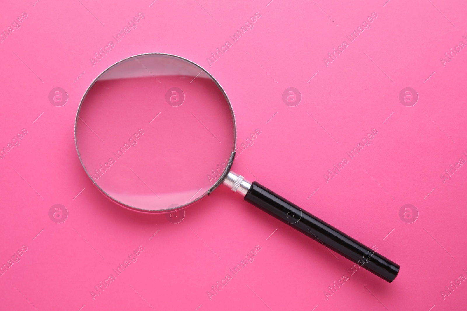 Photo of Magnifying glass on pink background, top view