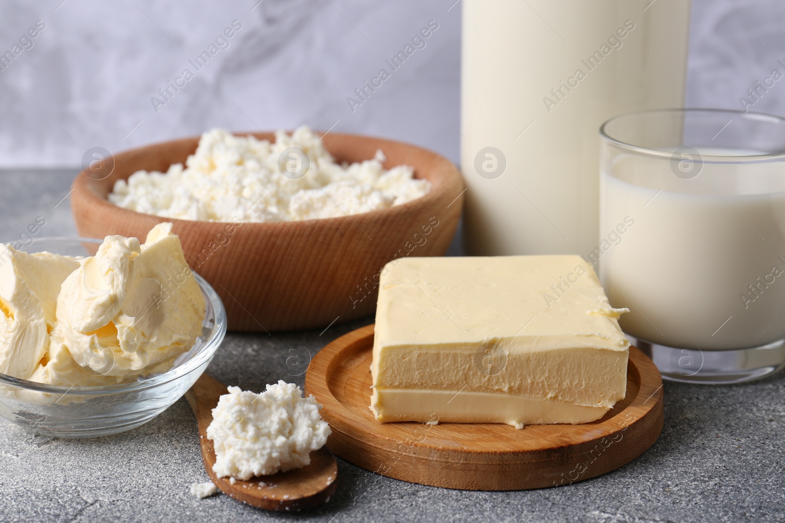 Photo of Piece of tasty homemade butter and dairy products on grey table