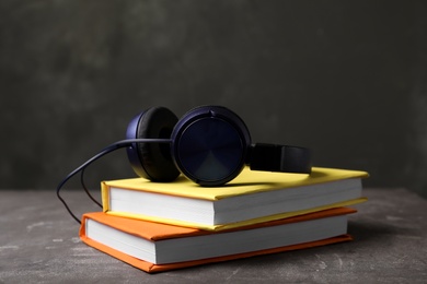 Photo of Modern headphones with hardcover books on table