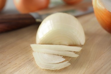 Photo of Partially sliced onion on wooden board, closeup