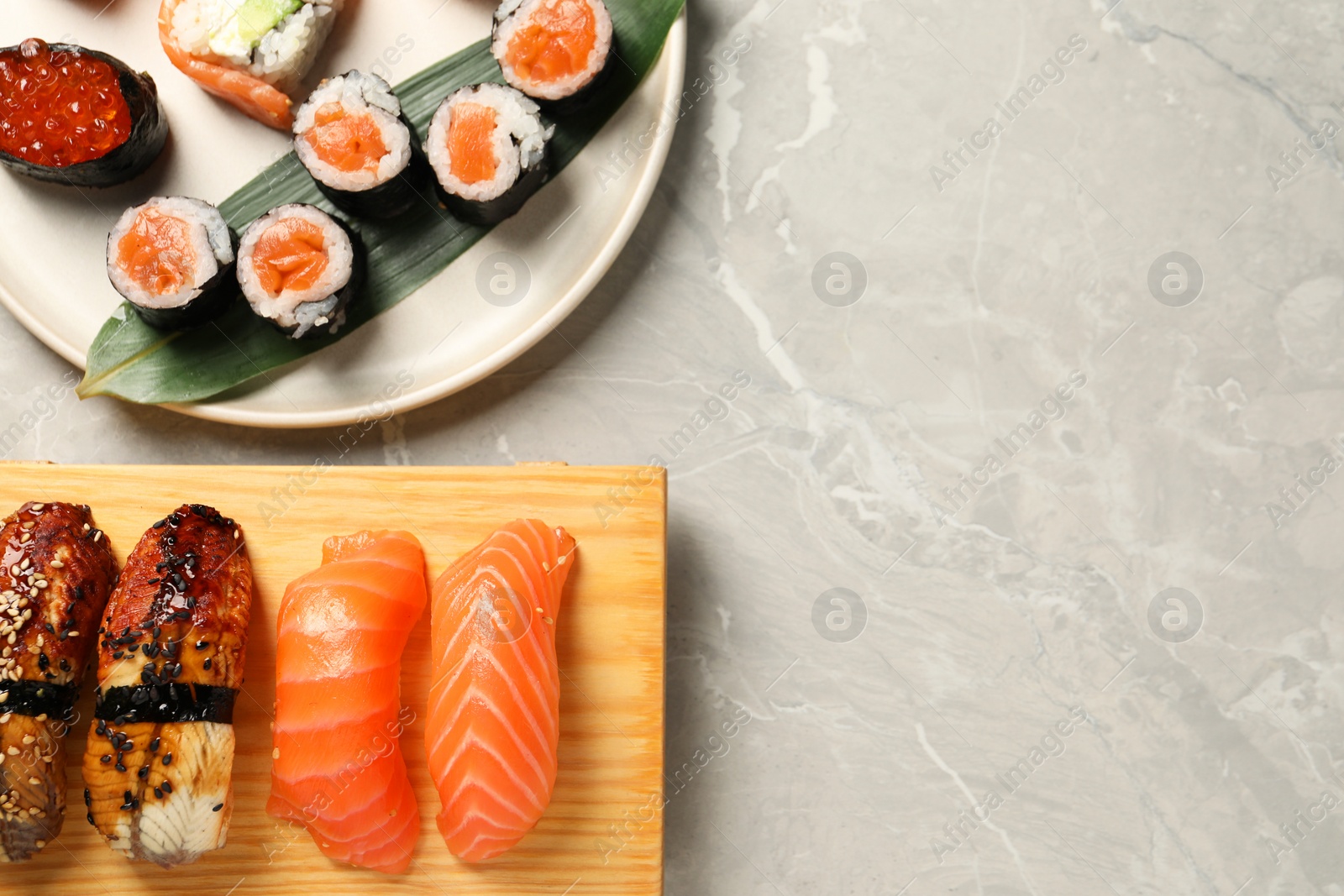 Photo of Delicious sushi rolls on light grey marble table, flat lay. Space for text