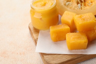 Frozen pumpkin puree cubes with ingredient on beige table, closeup. Space for text