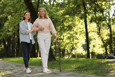 Photo of Senior lady with walking cane and young woman in park. Space for text