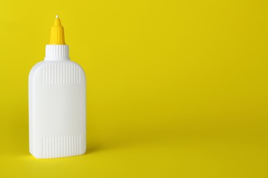 Bottle of glue on yellow background, space for text