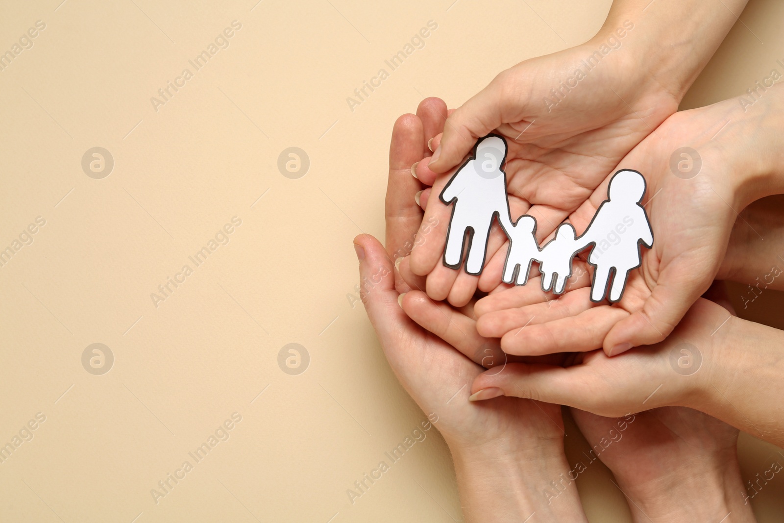 Photo of People holding paper family cutout on beige background, top view. Space for text