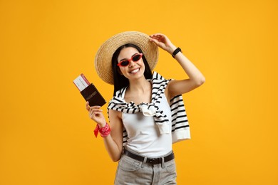 Photo of Happy female tourist with ticket and passport on yellow background