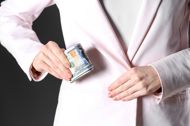 Photo of Woman putting bribe into pocket on black background, closeup