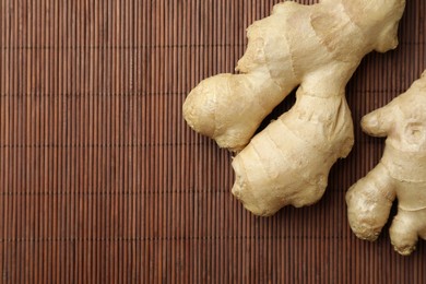 Photo of Fresh ginger on bamboo mat, top view. Space for text