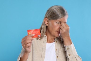 Photo of Upset woman with credit card became fraud victim on light blue background