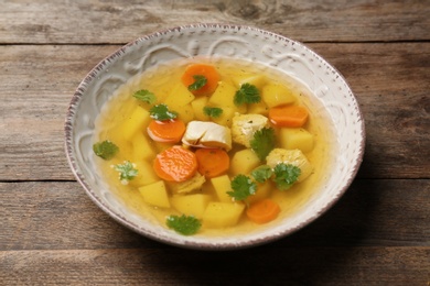 Photo of Dish with fresh homemade chicken soup on wooden table