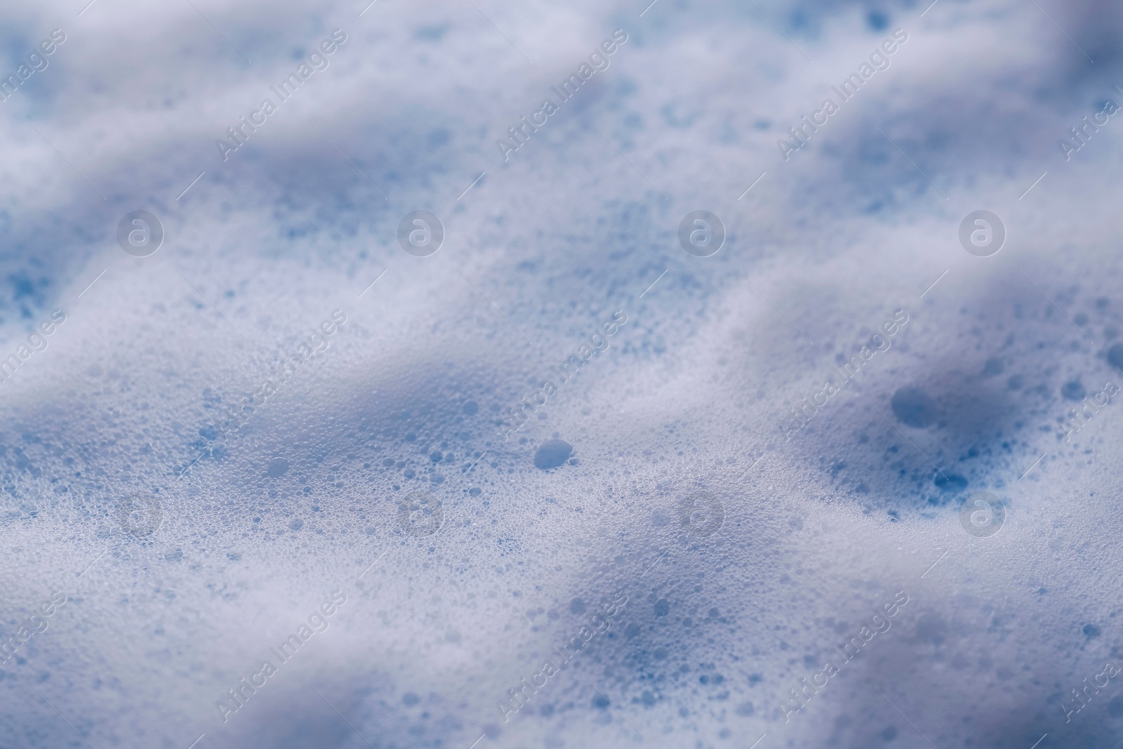 Photo of White foam on light blue background, closeup