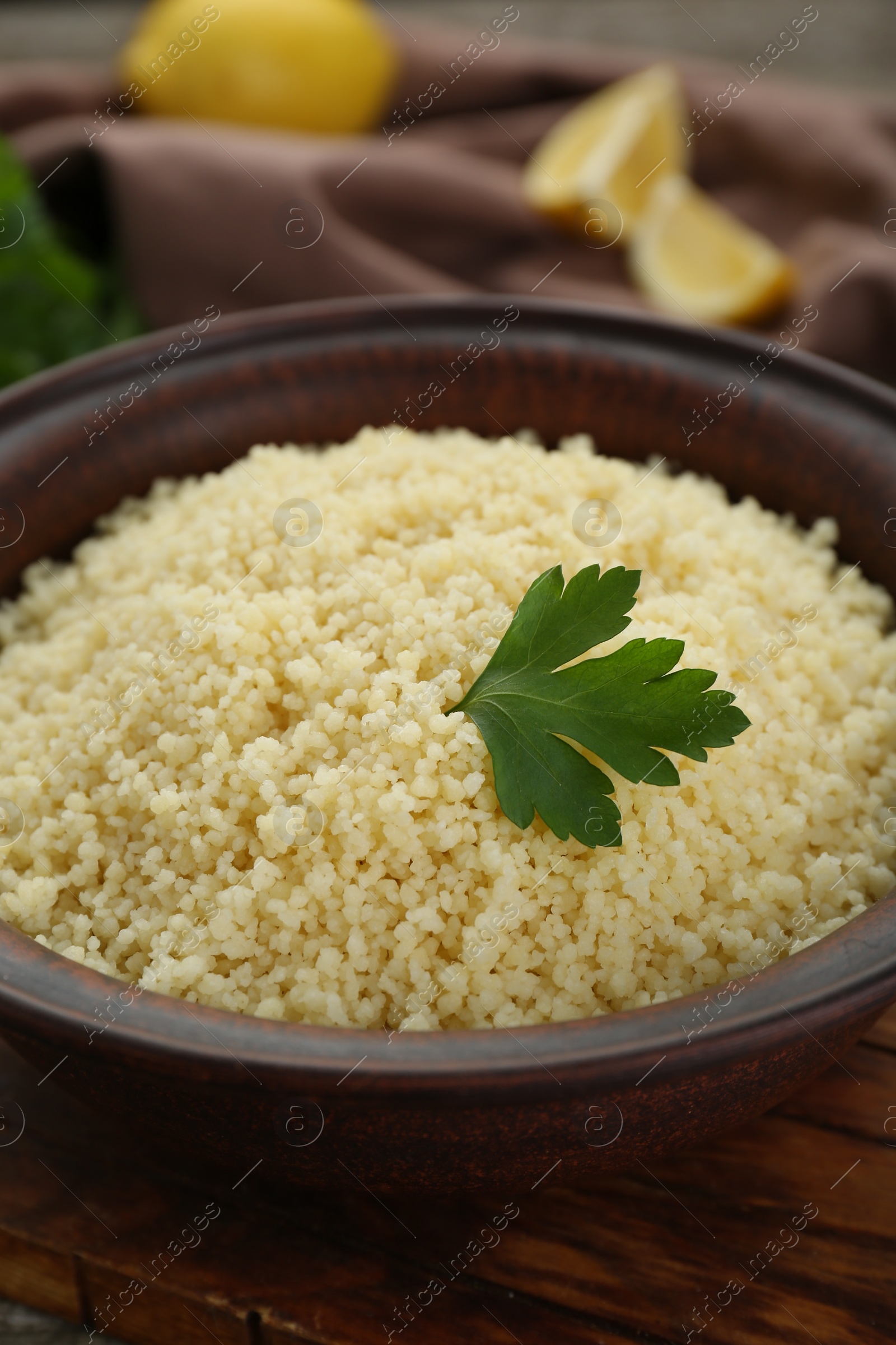 Photo of Tasty couscous with parsley on wooden board, closeup