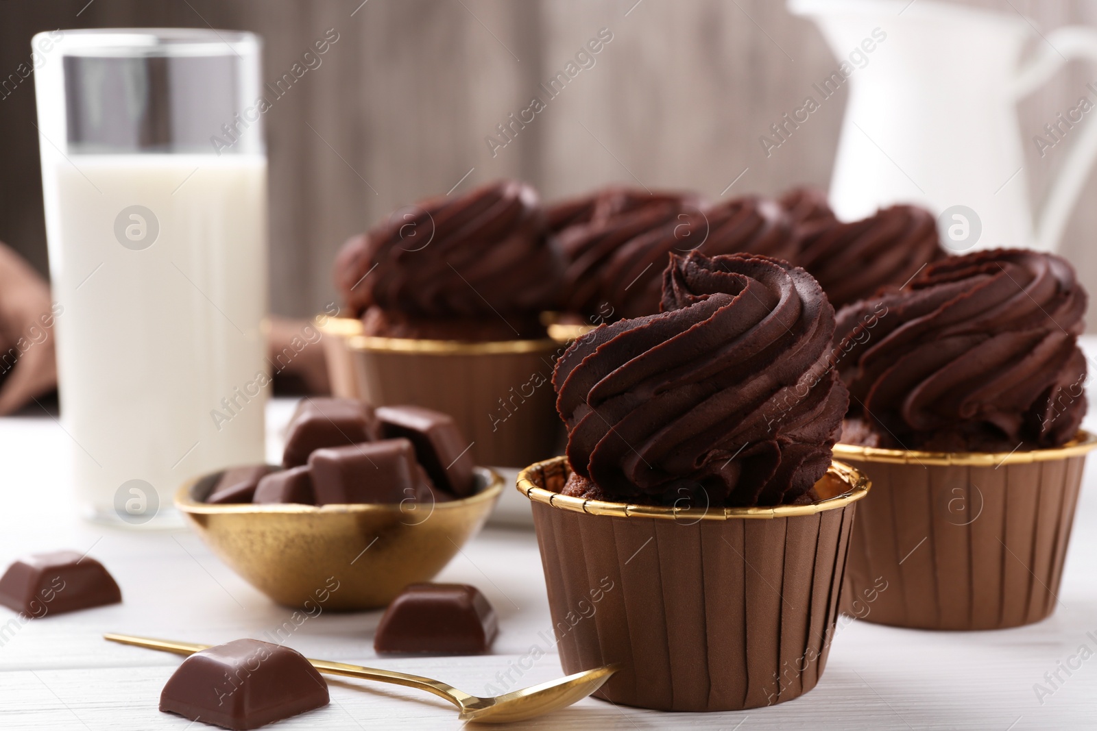 Photo of Delicious cupcake and chocolate pieces on white wooden table