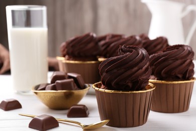Photo of Delicious cupcake and chocolate pieces on white wooden table