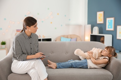 Photo of Female psychologist working with cute little girl in office