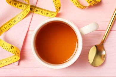 Flat lay composition with herbal diet tea and measuring tape on pink wooden table. Weight loss concept