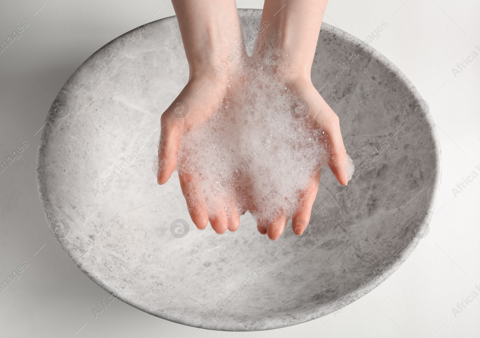 Photo of Woman washing hands with cleansing foam near sink in bathroom, top view