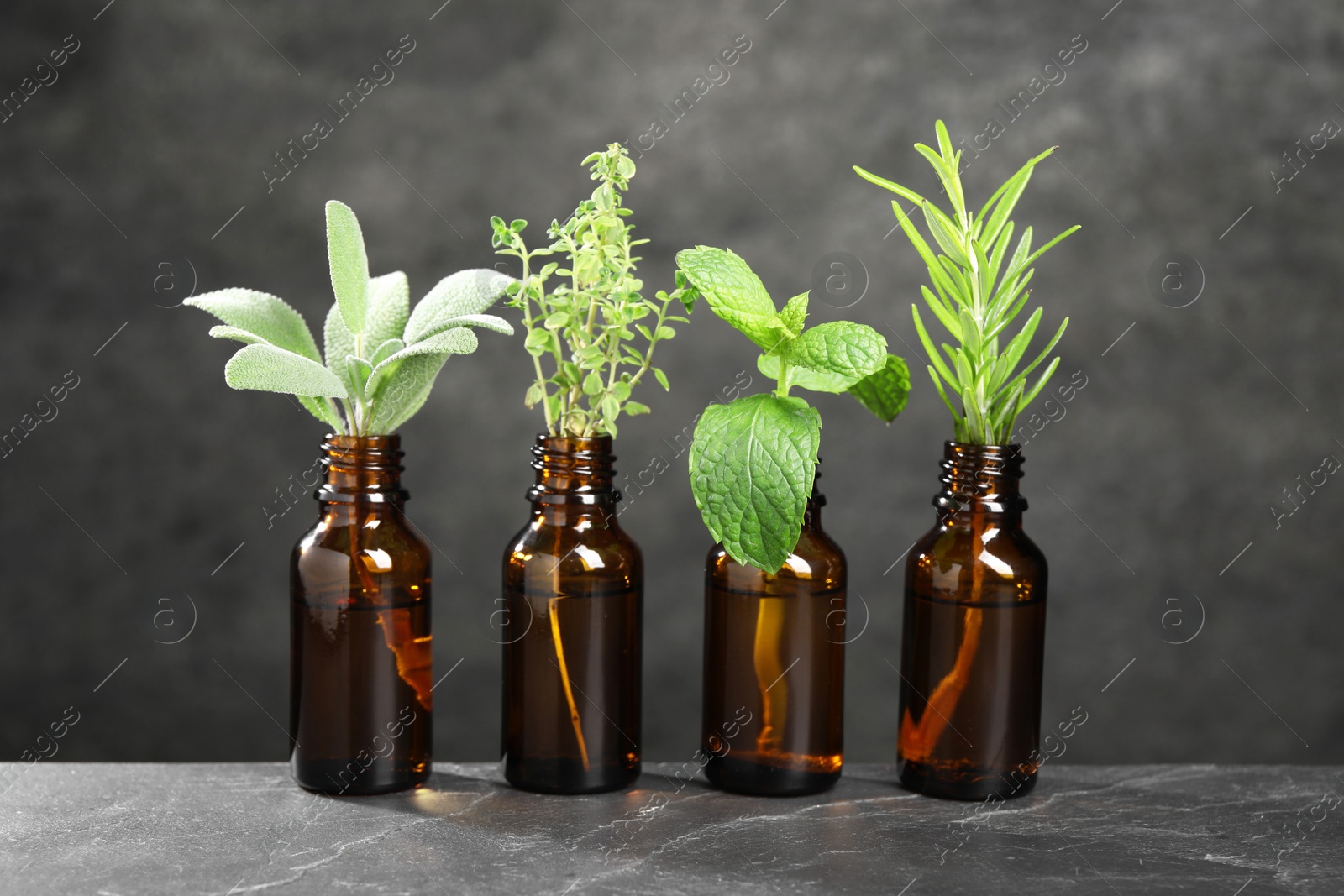 Photo of Bottles with essential oils and plants on grey textured table