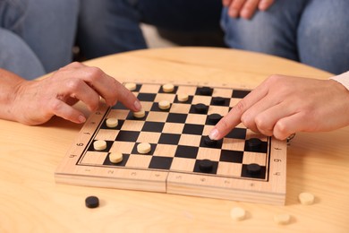 People playing checkers at wooden table, closeup