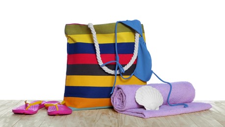 Photo of Stylish bag, sea shell and other beach accessories on wooden table against white background