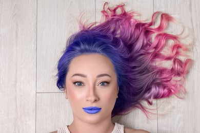 Trendy hairstyle. Young woman with colorful dyed hair on white wooden background, top view