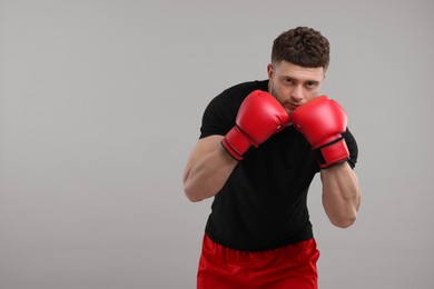 Man in boxing gloves on grey background. Space for text