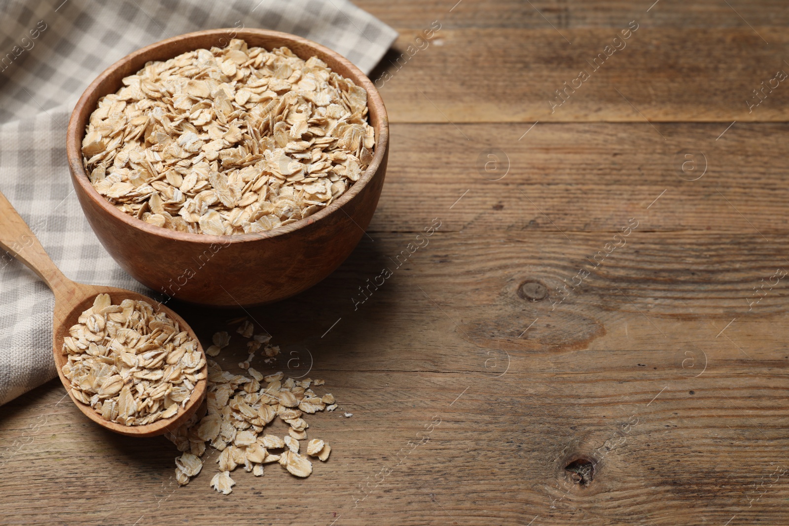 Photo of Bowl and spoon with oatmeal on wooden table, space for text