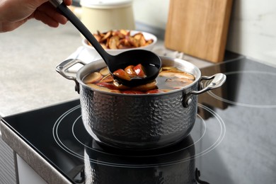 Photo of Woman making delicious compot in pot on stove, closeup