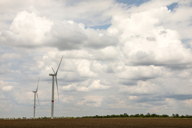 Modern wind turbines in field on cloudy day. Alternative energy source