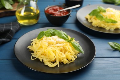 Photo of Tasty spaghetti squash with basil and cheese served on blue wooden table