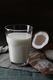 Photo of Glass of coconut milk, flakes and nut pieces on wooden table