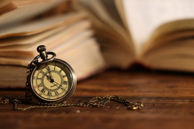 Pocket clock with chain on wooden table, closeup. Space for text