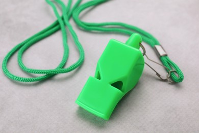 Photo of One green whistle with cord on light grey table, closeup