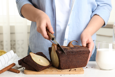 Woman cutting tasty pear bread at table, closeup. Homemade cake